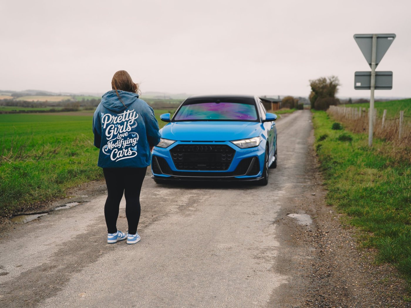 Pretty Girls Love Modifying Cars hoodie worn beside a blue Audi